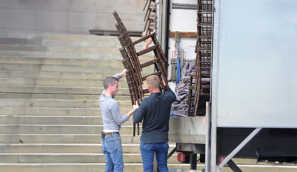 Two Men Carrying Chairs